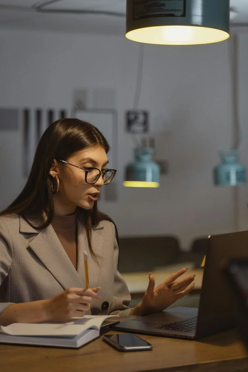 Young professional woman smiling in modern office environment with laptop